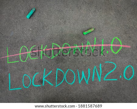The inscription text on the grey board, strike out lockdown 1.0 and lockdown  2.0   Using color chalk pieces. Royalty-Free Stock Photo #1881587689