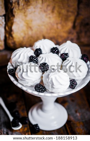 Meringue cookies with blackberries on rustic background