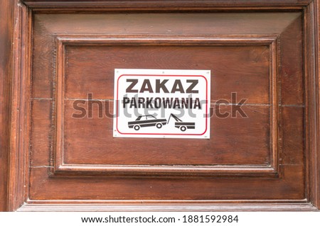 Polish Warning sign on a wooden door saying parking not allowed 