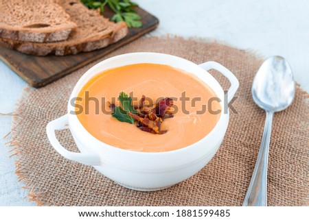 Pumpkin soup with fried bacon in white tureen on a white background with bread and parsley. Top view. Copy cpase