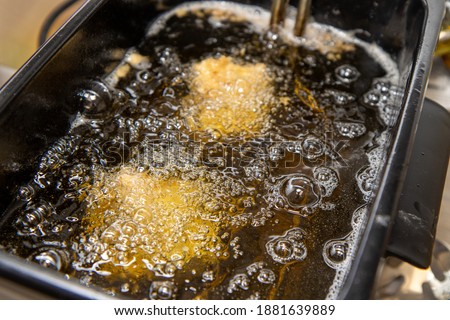 A oil frier with food and chicken cooking in the frier Royalty-Free Stock Photo #1881639889