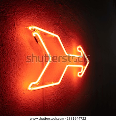Neon arrow signage at dark wall