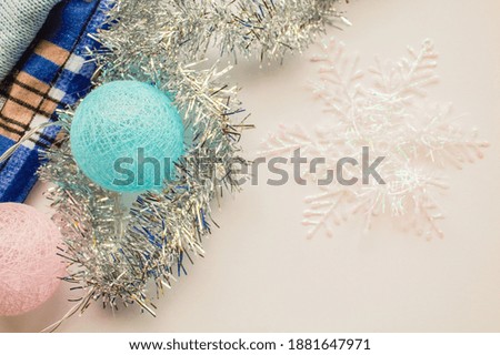 Garland of balloons and silver tinsel next to a snowflake on a white background view from above