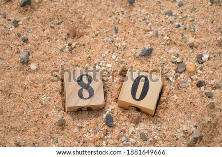 Number 80, rating, award, Cover design in natural concept with a number cube on sand background.