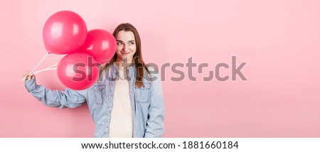 Young caucasian woman holding balloons with happy expression and celebrating a Valentine's day isolated over a pink background