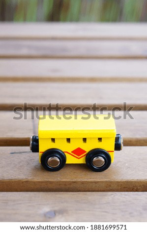 A vertical closeup shot of a yellow wooden toy train on a wooden table