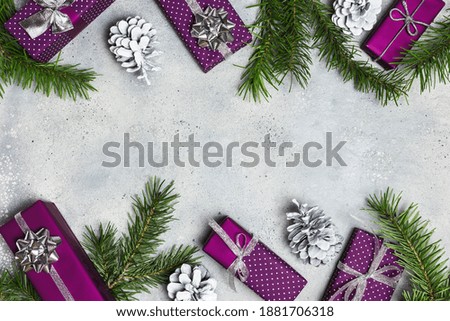 Christmas or winter composition. Christmas gifts, fir tree branches, and ornaments on gray stone background. Flat lay, top view, copy space.