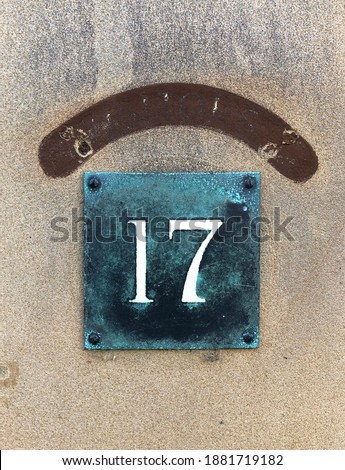 Enameled house number seventeen. White numbers on a green background

