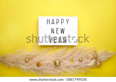 Pampas grass with golden decor and lightbox on trendy yellow color background. Cortaderia selloana. Top view. Copy space. Christmas, New Year concept.