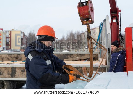 Assemblers unload ice panels from a car using a crane