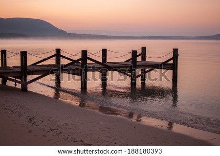 Dock on calm water at sunrise in winter