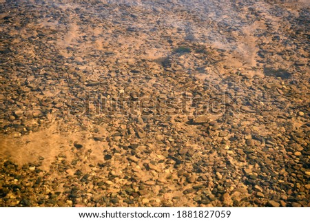 Stones and pebbles at the bottom of a pond under water. Underwater mineral background.