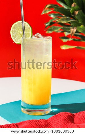 Yellow Mango Lemonade with Lime Slice and Metal Straw on Red Background