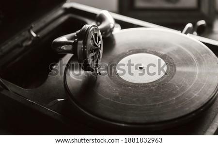 Vintage phonograph with black vinyl record plays an old music, sepia toned vintage stylized monochrome photo Royalty-Free Stock Photo #1881832963
