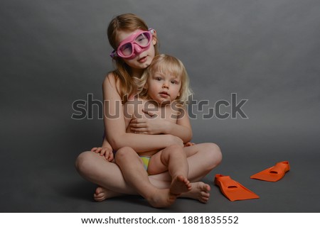 Big sister and young brother in swimwear getting ready for a beach holiday
