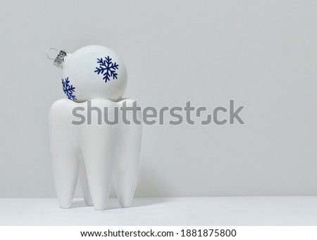 Universal Christmas ball of white color in a glass in the shape of a tooth