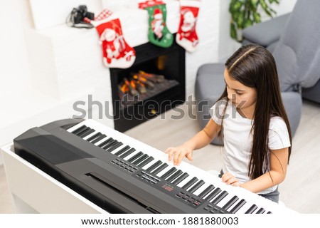 Cute little girl play Christmas melody on piano, merry Christmas celebration, happy seasonal holidays