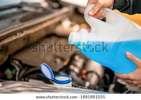 Pouring antifreeze. Filling a windshield washer tank with an antifreeze in winter cold weather.