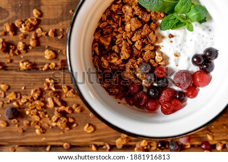 Top view of healthy bowl with berries, mint and granola on wooden board. Concept for cafes and restaurants. Food photo. Healthy food. Dieting. Spring menu. Vegetarian food