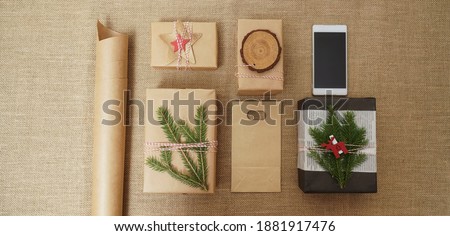pine branches, gift box, wooden deers and screen of mobile phone  on sackcloth  background. Space for text. Top view. Flat lay. 2021 happy new year. Christmas composition