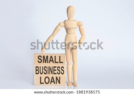 Wooden man shows with a hand text SMALL BUSINESS LOAN concept on wooden block