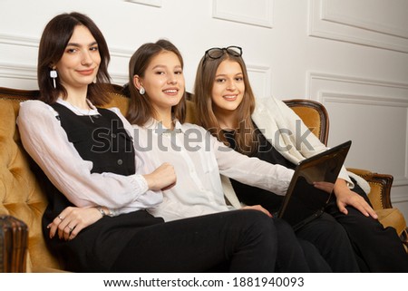 three young women on the couch at the laptop