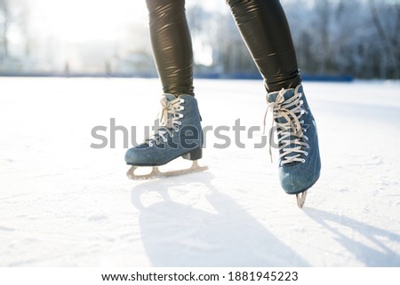 Photo of blue skates with white lacing against the background of sun glare in winter.