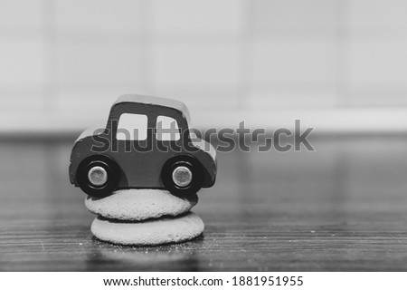A grayscale shot of a wooden toy car on the cookies on the table