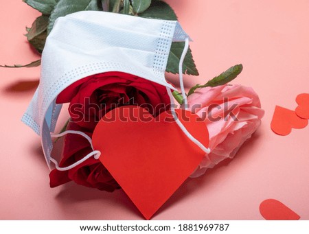 Roses on a pink background and a medical mask with a card for valentine's day .. Creative background for valentine's day.Close-up.