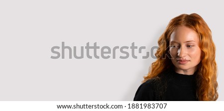 Banner. Beauty portrait. Cute red-haired girl on a white background with side space for advertisment
