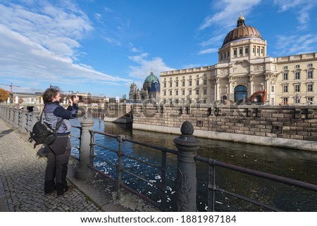 a tourist is taking a photograph of the Royal Castle Berlin Germany in afternoon sun and blue sky, a building site in front of the building