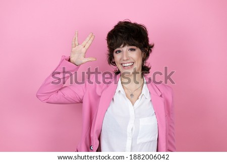 Young business woman over isolated pink background doing hand symbol