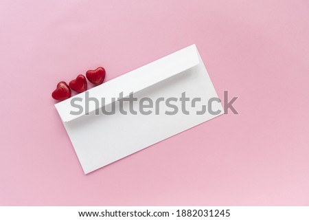 A letter card with small red hearts on a pink background