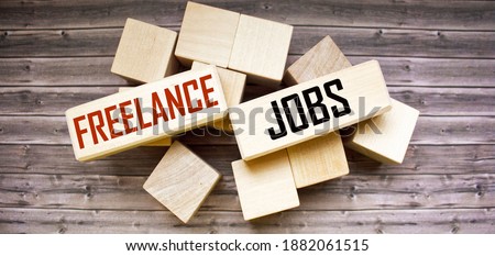 FREELANCE JOBS written on construction blocks on a wooden background. Business concept