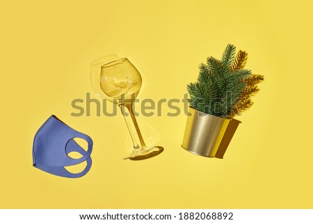 Small fir tree in golden metal basket vine glass and mask isolated on bright yellow background. High quality photo