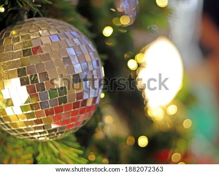Christmas Tree fir close up decoration with big silver mirror and golden glitter ball has blur bokeh light background selective focus, has copy space for Christmas season, invitation card background.