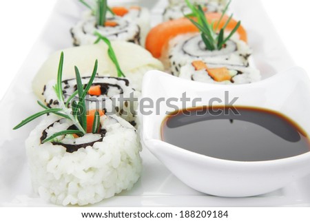 Maki Rolls and California rolls made of fresh raw Salmon, Tuna and Eel with Cream Cheese and Avocado . Isolated over white background . on long white plate . Maki Sushi and Nigiri