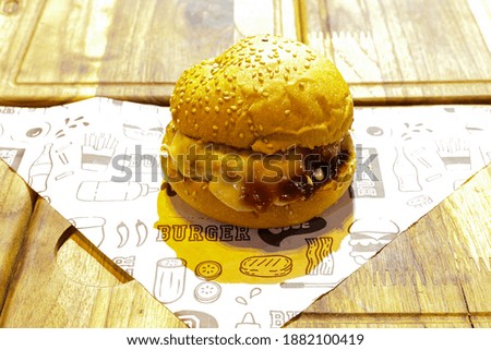 burger with cheese, bacon, salad and vegetables on a wooden board