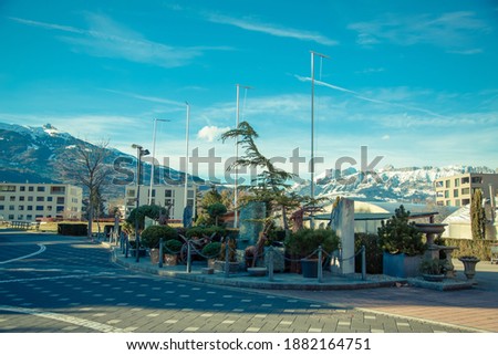Alps mountains in Liechtenstein. Medieval House and vineyards in the capital of Liechtenstein in the city of Vaduz on the background of residential buildings, blue sky and snow-capped mountains 