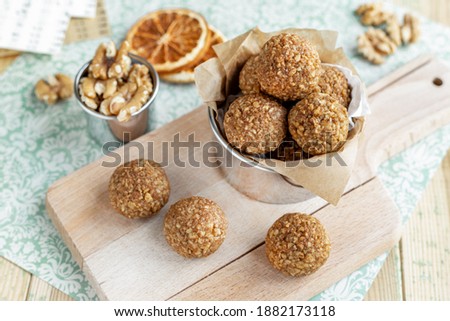 Caramelized walnut balls on wood board and mint background, orange scented healthy nut cookies, homemade simple Christmas treats baking recipes Royalty-Free Stock Photo #1882173118