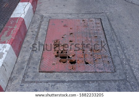 Selective focus of broken steel drain cover on street   