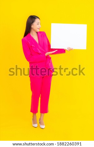 Portrait beautiful young asian woman with empty white billboard on yellow isolated background