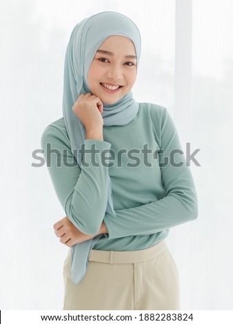 Portrait of 30s beautiful Muslim girl wearing hijab traditional religious cloth use hand touch her chin and looking to camera with a lovely smile on white background. Royalty-Free Stock Photo #1882283824