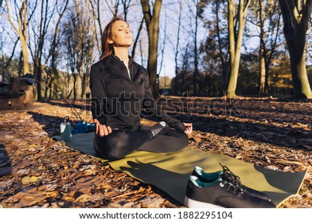 Beautiful woman practiced yoga in autumn or winter in the forest or park. outdoor sport concept