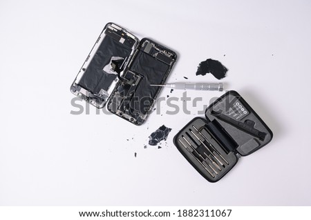A top view of a broken smartphone and repairing too on a white surface