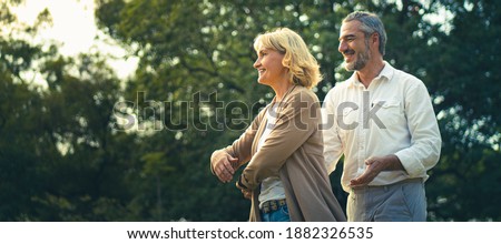 Happy elderly dancing together at outdoor in the park with warming sunlight atmosphere, Worry free for retirement senior people, Lovely older lifestyle healthy and happiness. Old age healthy couple.