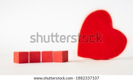 four red cubes and red wooden heart standing isolated on white background
