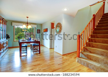 Open dining area with served table and cabinet. View of staircase