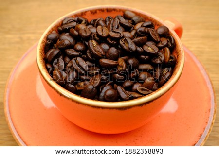 
Rose ceramic coffee cup on wooden table and fresh coffee beans inside, delicious coffee, macro shots, coffee and drinks