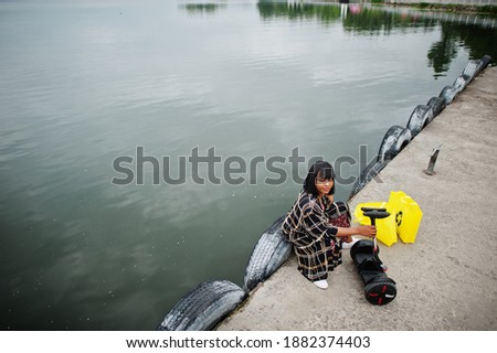Beautiful african american woman sit near segway or hoverboard. Black girl with yellow  cloth eco bags recycling symbol.